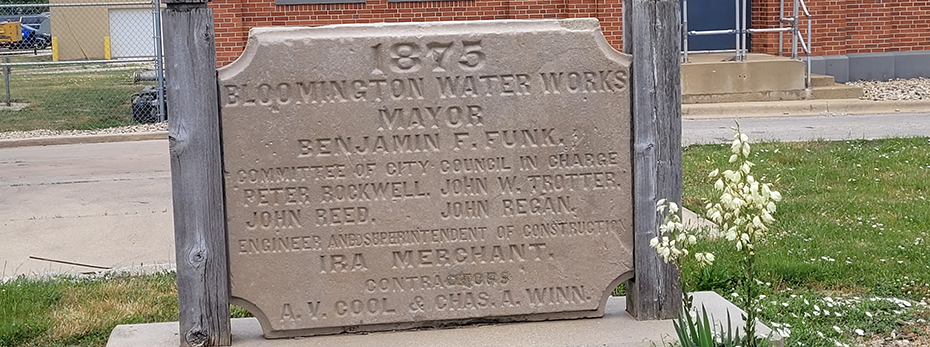 A concrete sign with wooden posts that says 