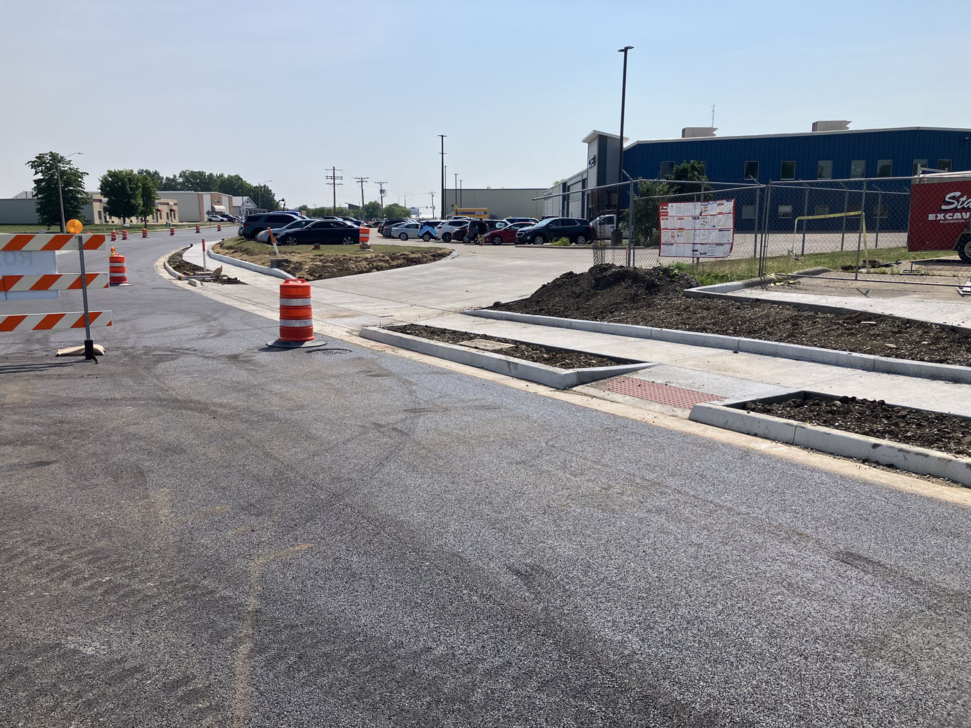 Sidewalk, ramps, curb, and gutter next to a recently installed asphalt road.
