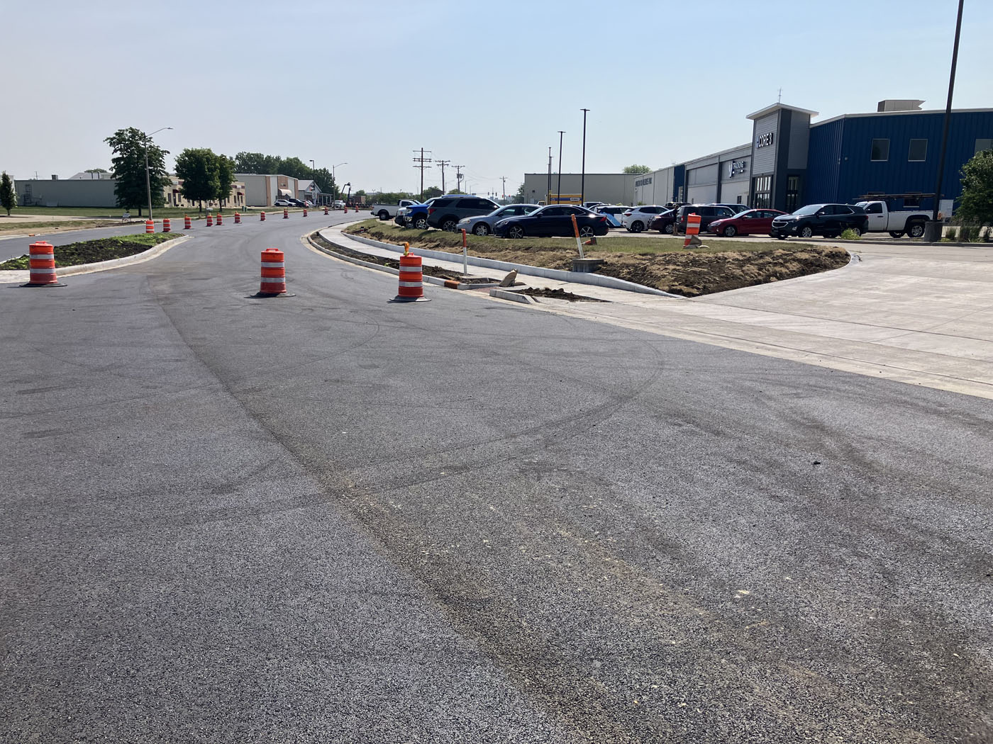 A recently installed asphalt road intersection with sidewalk, curb, gutter, and ramps.